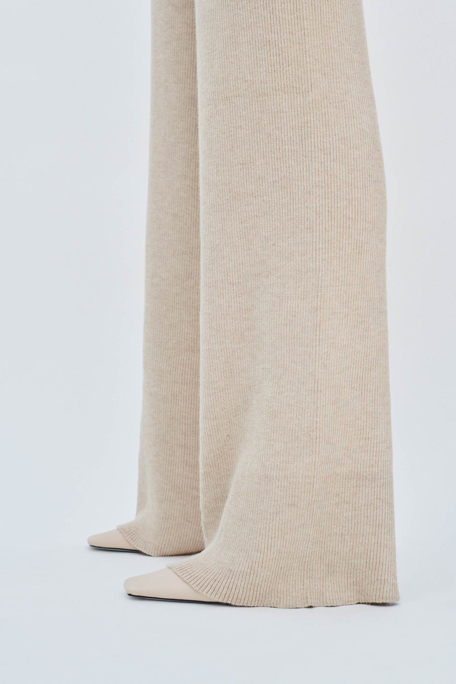Model wearing AQVAROSSA Berkane Flowy Trousers in colour oat in silk alpaca fabric bottom view
